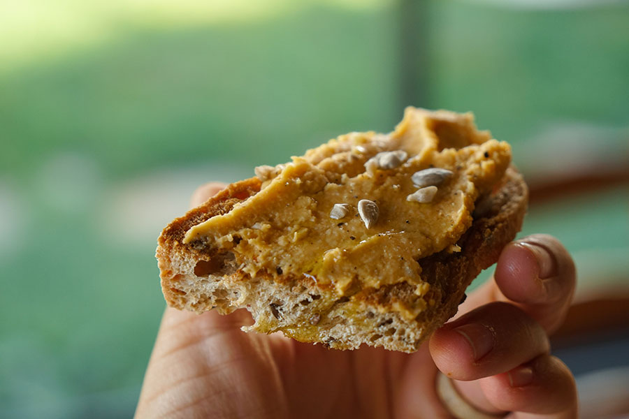 Paté de boniato sobre una tostada crujiente, un chorrito de aceite y unas semillas de girasol